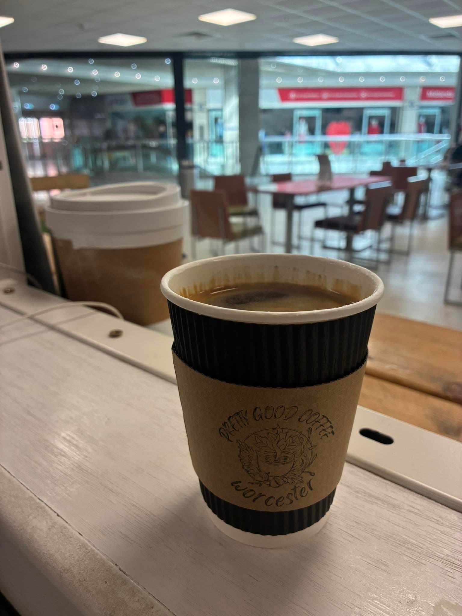 A Pretty Good Coffee takeaway cup with the Worcester logo sleeve, at the Crowngate Heritage Pod